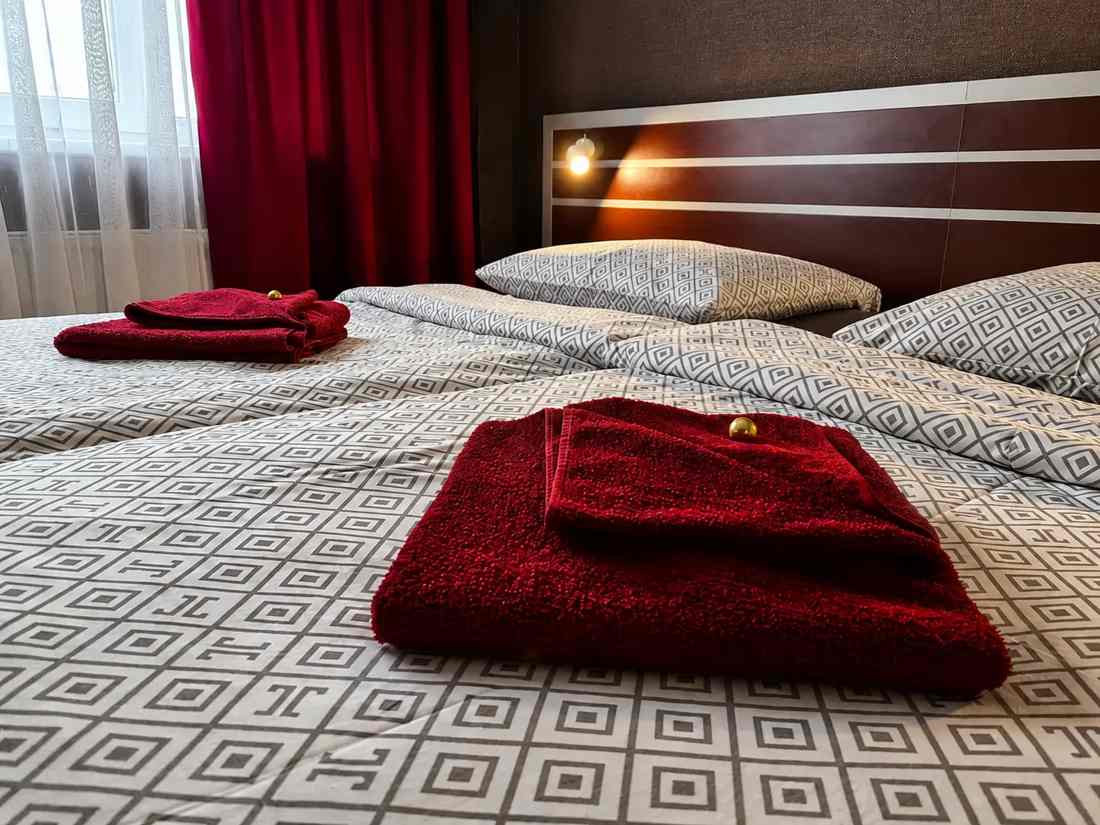 Doppelzimmer im Hotel 108 mit zwei Decken und gefalteten roten Handtüchern